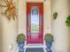 Elegant front entrance with a decorative red door, stylish planters, and unique wall decor at 1958 Marshberry Ct, Trinity, FL 34655