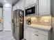 Kitchen with stainless steel refrigerator and modern appliances, complemented by stone countertops and tiled backsplash at 1958 Marshberry Ct, Trinity, FL 34655