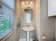 Stylish powder room featuring a pedestal sink, oval mirror, and modern fixtures at 1958 Marshberry Ct, Trinity, FL 34655