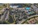 Aerial view showcasing community amenities, including a clubhouse, pool, ponds, tennis courts, and parking at 2006 Hadrian Ct, Sun City Center, FL 33573