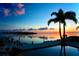 Stunning sunset view of pool with palm trees and bay reflecting blue and orange sky colors at 2279 Mermaid Ne Pt, St Petersburg, FL 33703