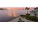 Waterfront view featuring a patio with pool, lounge chairs, and lush tropical landscaping at sunset at 2279 Mermaid Ne Pt, St Petersburg, FL 33703