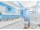 Bright bathroom with double vanity sinks, marble countertops, and tiled shower-tub combo at 412 Manor Blvd, Palm Harbor, FL 34683