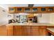 Bright open kitchen with wood cabinetry and view into Gathering room with fireplace at 412 Manor Blvd, Palm Harbor, FL 34683