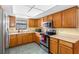 Well-lit kitchen features wood cabinetry, stainless appliances, and durable tile flooring at 412 Manor Blvd, Palm Harbor, FL 34683