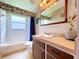 Bright bathroom featuring a single sink vanity, toilet, shower and a window providing natural light at 4315 Whittner Dr, Land O Lakes, FL 34639