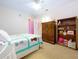 Bright bedroom has a bed with a quilt, a fan, a bookcase, a dresser, and pink walls in the doorway at 4315 Whittner Dr, Land O Lakes, FL 34639