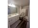 Bathroom featuring double sinks with white cabinets, a shower/tub combo, and wood-look flooring at 4743 Deer Track St, Tampa, FL 33610