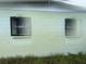 Close up of light green single-story home with window bars and overgrown yard at 4920 S 82Nd St, Tampa, FL 33619