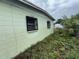 Light green single-story home with dark window bars and overgrown yard at 4920 S 82Nd St, Tampa, FL 33619