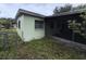 Side corner of light green home with screened porch and overgrown yard at 4920 S 82Nd St, Tampa, FL 33619