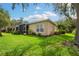 Beautifully landscaped backyard with lush green grass, mature trees, and a screened patio at 5143 Lochmead Ter, Zephyrhills, FL 33541
