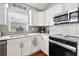 Close-up of the kitchen with white cabinets, tile backsplash, and stainless steel appliances at 5143 Lochmead Ter, Zephyrhills, FL 33541