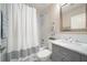 Clean bathroom with tub, toilet, grey vanity, and decorative white shower curtain at 670 42Nd Ne Ave, St Petersburg, FL 33703