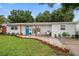 Inviting front yard features a stone walkway, lush green lawn, and meticulously arranged flowerbeds at 670 42Nd Ne Ave, St Petersburg, FL 33703
