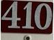 Close-up of unit number 410 on a dark red background with large silver numbers at 701 S Madison Ave # 410, Clearwater, FL 33756