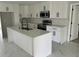 Modern kitchen featuring an island with white cabinets, new stainless steel appliances, and marble tile flooring at 7021 Parliament Dr, Tampa, FL 33619