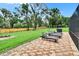 Lounge chairs are placed on the brick-paved backyard patio that overlooks the expansive lawn and wooden fence at 8222 Valrie Ln, Riverview, FL 33569