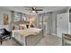 A well-lit bedroom with a ceiling fan, two windows, gray curtains, and a queen-sized bed with decorative pillows at 8222 Valrie Ln, Riverview, FL 33569