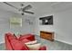 Red sofa, ceiling fan, and media center in game room with a large window and natural light at 8222 Valrie Ln, Riverview, FL 33569