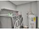 Bright laundry room with modern washer, dryer, shelves, and a water heater at 8222 Valrie Ln, Riverview, FL 33569