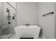 A sleek bathroom featuring a standalone soaking tub, a glass enclosed shower, and neutral walls with a modern aesthetic at 8752 Loft Pt, Wesley Chapel, FL 33545