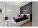 This bedroom features a luxurious platform bed with black furnishings, a unique accent wall and modern chandelier at 8752 Loft Pt, Wesley Chapel, FL 33545
