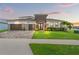 Stunning two-story home featuring a three-car garage, paver driveway, and beautifully manicured lawn at 8752 Loft Pt, Wesley Chapel, FL 33545