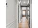 A bright hallway with wood floors leads to a bedroom area with wood paneled accent walls and dark colored trim at 8752 Loft Pt, Wesley Chapel, FL 33545