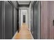 Hallway with modern wall paneling, wood flooring, and a view of the doors leading to rooms at 8752 Loft Pt, Wesley Chapel, FL 33545