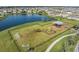 Aerial view of a fenced playground and soccer nets next to a large pond at 8752 Loft Pt, Wesley Chapel, FL 33545