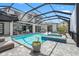 Spacious screened-in pool area with outdoor seating, hot tub, and lush landscaping at 8752 Loft Pt, Wesley Chapel, FL 33545