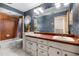 Cozy bathroom featuring blue floral wallpaper, a vanity with dual sinks and orange countertops, and a tub-shower combo at 9011 Baywood Park Dr, Seminole, FL 33777