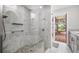 Luxurious shower with a glass enclosure, gray tiling, river rock floor, and access to the outdoor deck at 9011 Baywood Park Dr, Seminole, FL 33777
