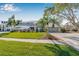 Landscaped front yard and a driveway leading to a home with a two-car garage with palm trees at 9011 Baywood Park Dr, Seminole, FL 33777