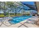 Sparkling pool enclosed in screened lanai with view of grassy backyard and mature trees at 9011 Baywood Park Dr, Seminole, FL 33777