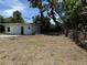 Backyard featuring an overgrown lawn with mature trees and a weathered building at 902 Marshall St, Clearwater, FL 33755