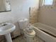 Bathroom view featuring a pedestal sink, toilet, and tiled bathtub, all in need of repair at 902 Marshall St, Clearwater, FL 33755