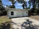 Exterior view of a detached white garage with concrete driveway, doors, and windows under a partly cloudy sky at 902 Marshall St, Clearwater, FL 33755