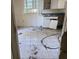 Damaged kitchen featuring tile flooring, a window, and older-style cabinetry with a broken door at 902 Marshall St, Clearwater, FL 33755
