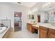 Well-lit bathroom featuring a double vanity, soaking tub, and seamless access to the primary bedroom at 10435 Deerberry Dr, Land O Lakes, FL 34638