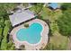 Aerial view of a large community pool with surrounding lounge chairs and covered pavilion with palm trees and a playground nearby at 10435 Deerberry Dr, Land O Lakes, FL 34638