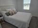 Bedroom showcasing LVP flooring, a comfy bed with floral pillows, and a bright window at 10573 Oakside Dr, Palmetto, FL 34221