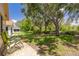 Lush backyard featuring verdant lawn, mature trees, patio area, and comfortable green outdoor chairs at 11078 Heathrow Ave, Spring Hill, FL 34609