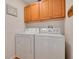 Bright laundry room featuring a white washer and dryer set with overhead wooden cabinets at 11078 Heathrow Ave, Spring Hill, FL 34609