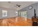 Bright living room featuring hardwood floors, a ceiling fan, large windows, and a sliding door to the patio at 11078 Heathrow Ave, Spring Hill, FL 34609