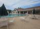 Resort-style pool features lounge chairs, tables, umbrellas, and a building with a balcony in the background at 11078 Heathrow Ave, Spring Hill, FL 34609