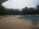 Community pool with lounge chairs and tables shaded by mature trees at 11078 Heathrow Ave, Spring Hill, FL 34609