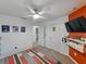 Modern bedroom with an orange accent wall, wall-mounted TV, and white walls at 11287 Cay Spruce Way, San Antonio, FL 33576