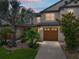 Charming townhome showcasing a well-manicured lawn, a brown garage door and mature trees and landscaping at 11287 Cay Spruce Way, San Antonio, FL 33576
